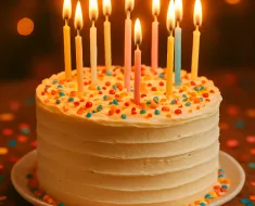 Bolo de aniversário lindamente decorado com velas acesas, cercado por confetes coloridos e um brilho festivo e acolhedor. O ambiente é íntimo e alegre, com um fundo suavemente desfocado, em estilo Pinterest.